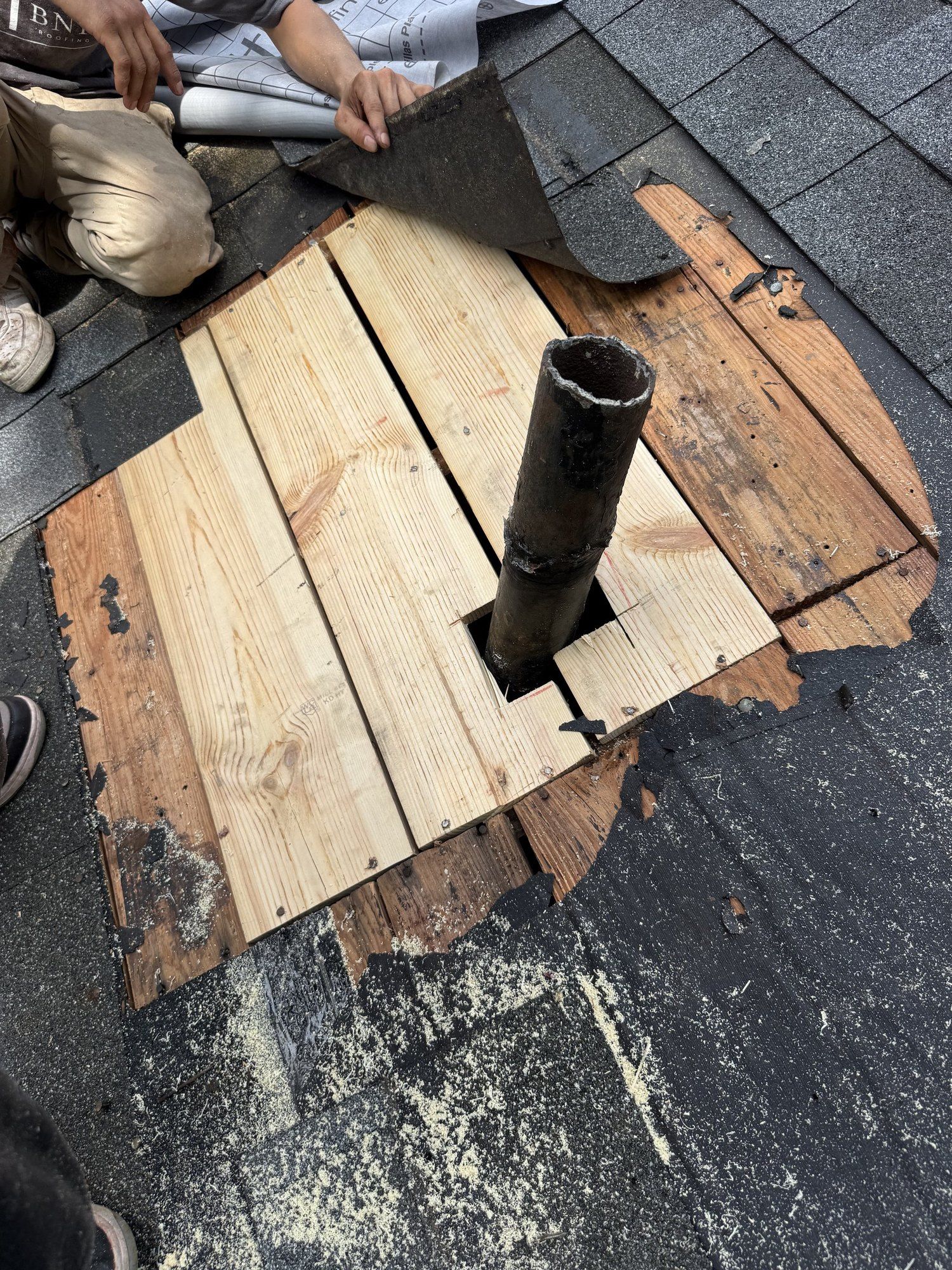 Rotted roof decking cut out around a plumbing vent pipe and replaced with new boards