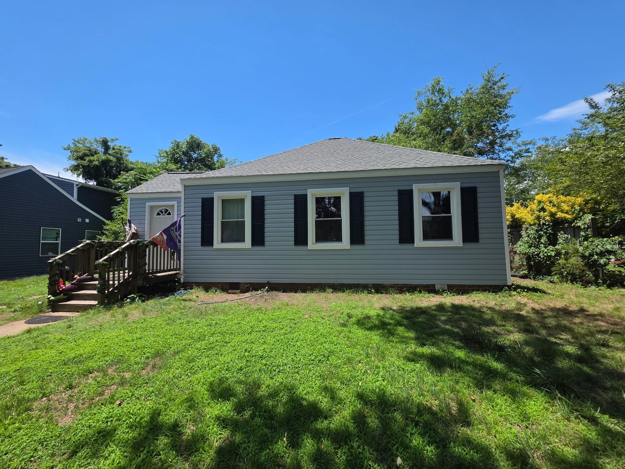 Single-story blue-gray ranch home with a new gray hip roof on a sunny day