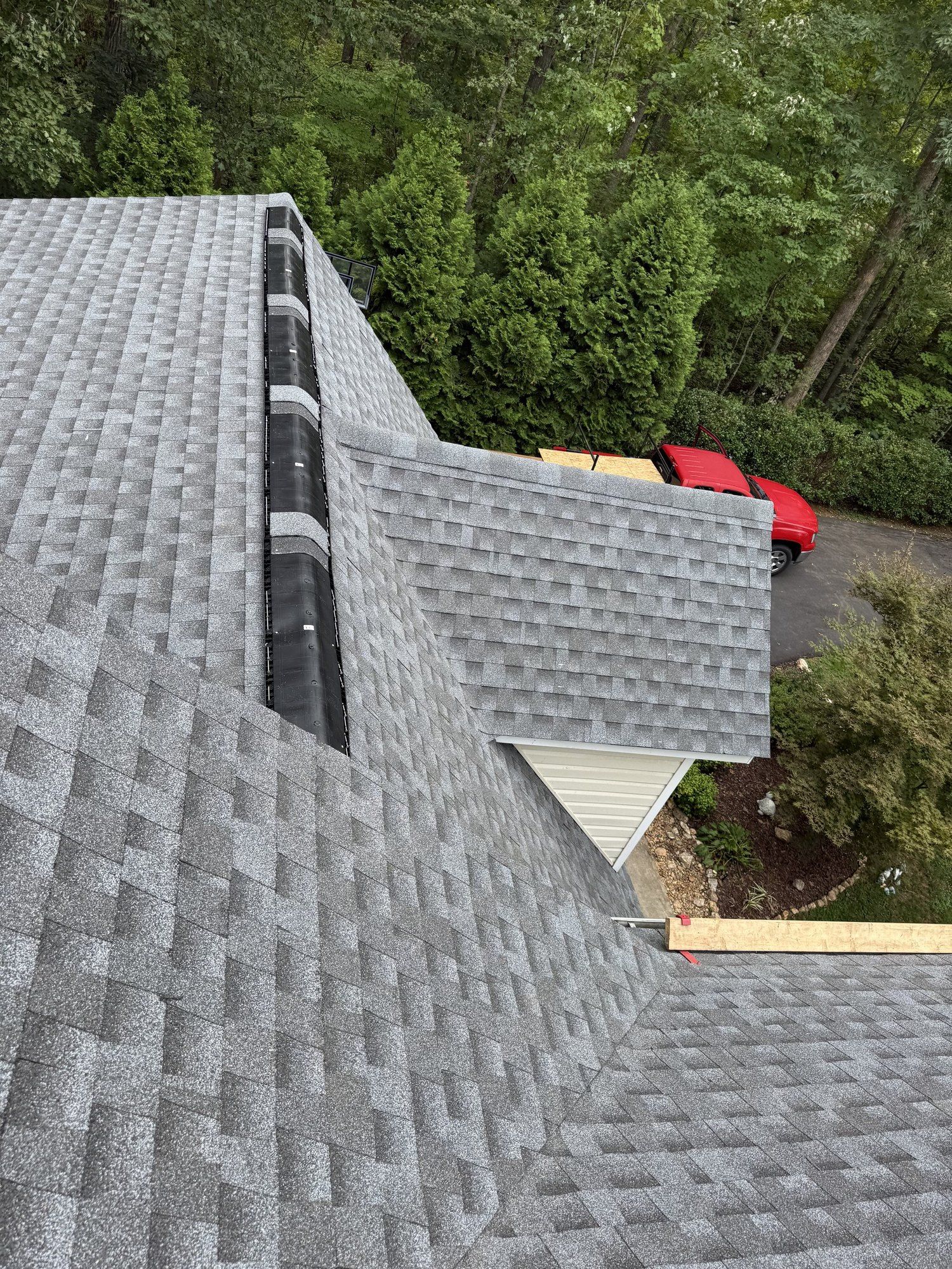 Ridge vent being installed along the peak of a new gray shingle roof