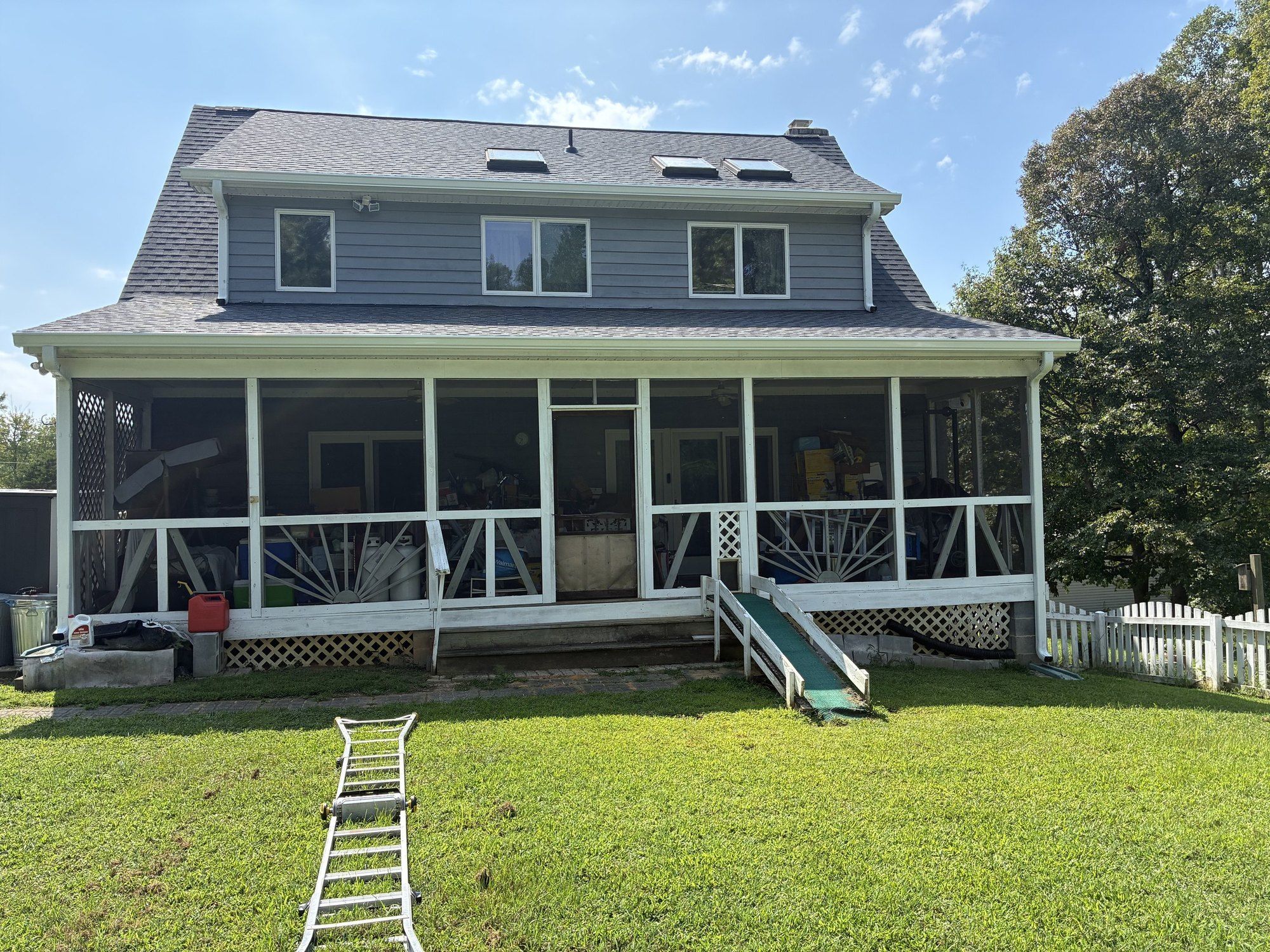 Back of a two-story blue-gray home with skylights, a screened porch and a new shingle roof