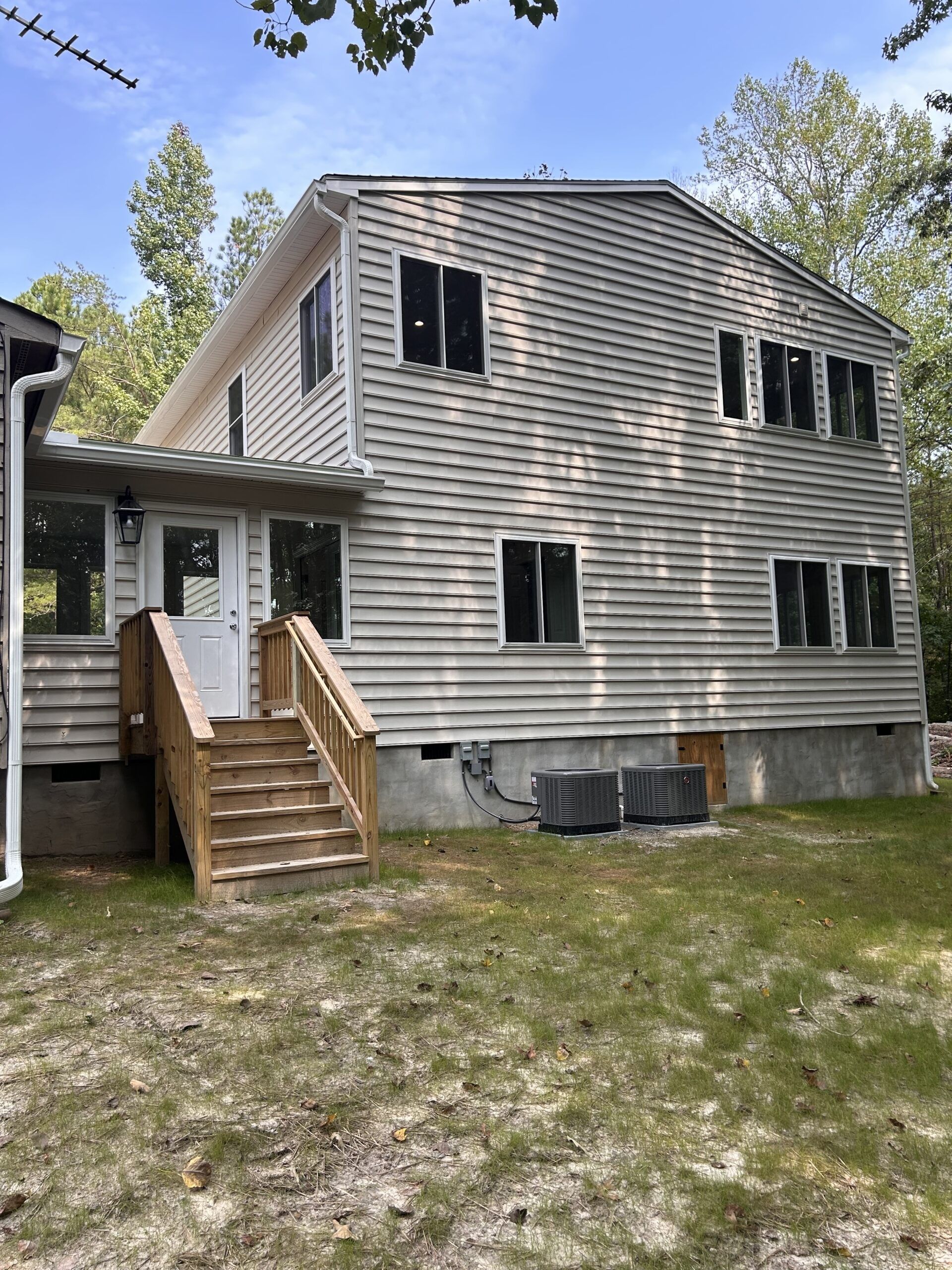 Two-story home with new light gray vinyl siding and a rear stair landing