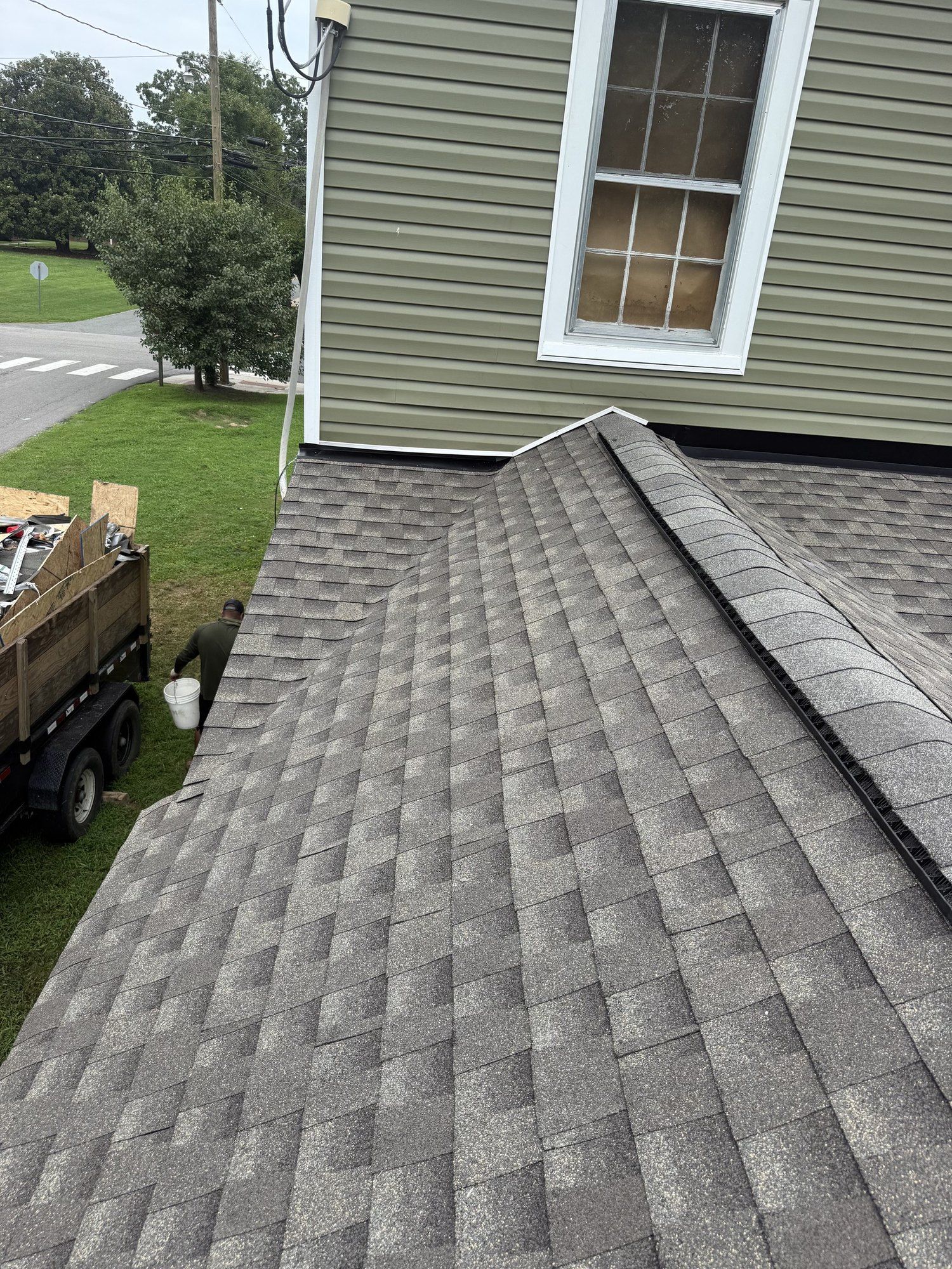 New shingle roof running up to a sided wall with step flashing tucked under the siding
